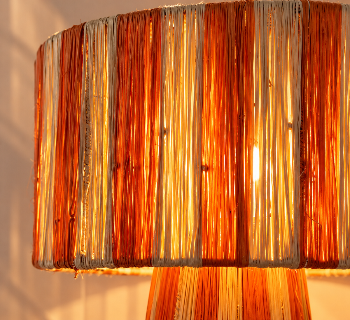 Détail de l’abat-jour cylindrique en raphia teinté orange brulé allumé