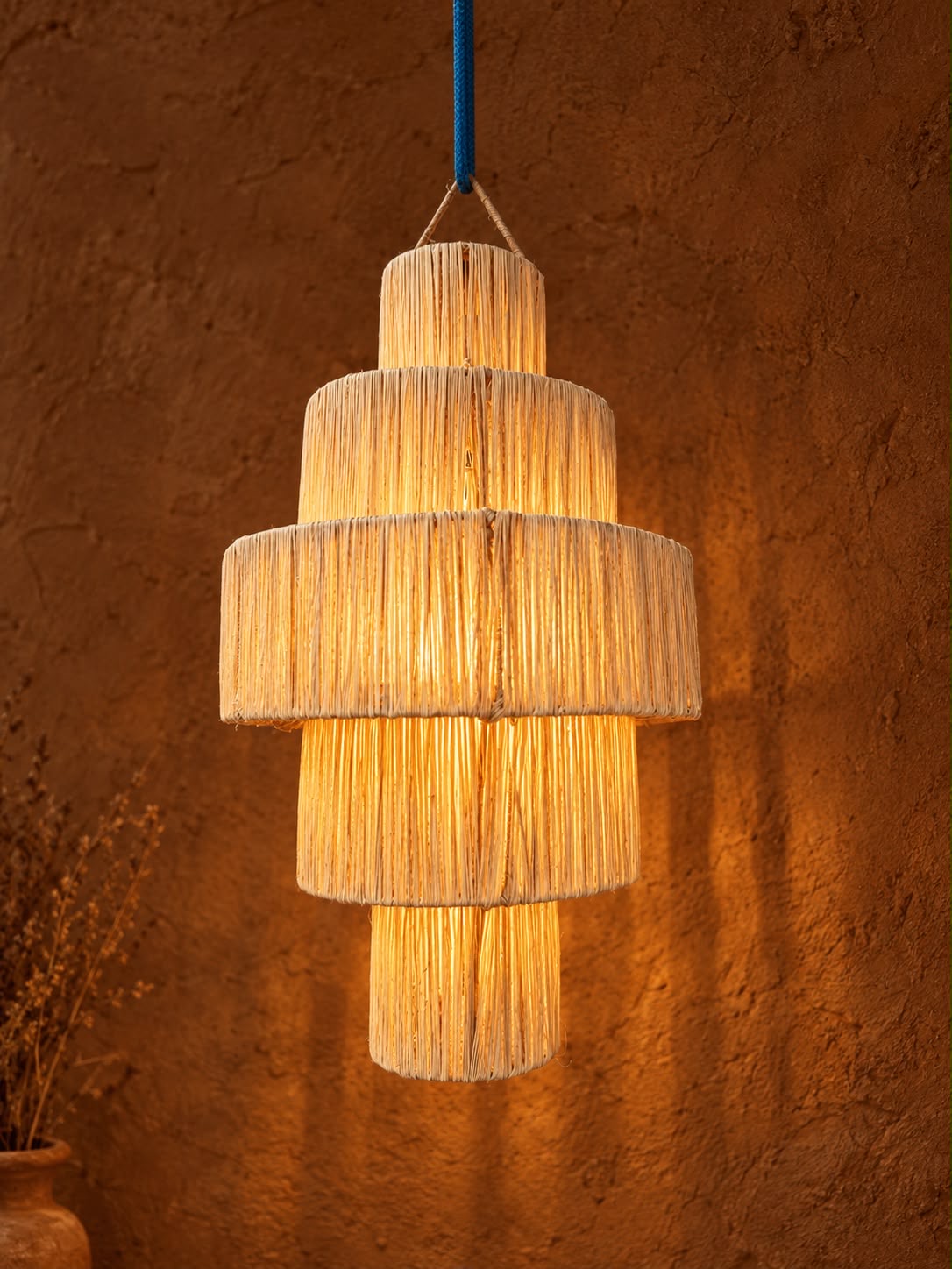 Suspension à niveaux en raphia tressé, lumière chaude ambreée, artisanat marocain
